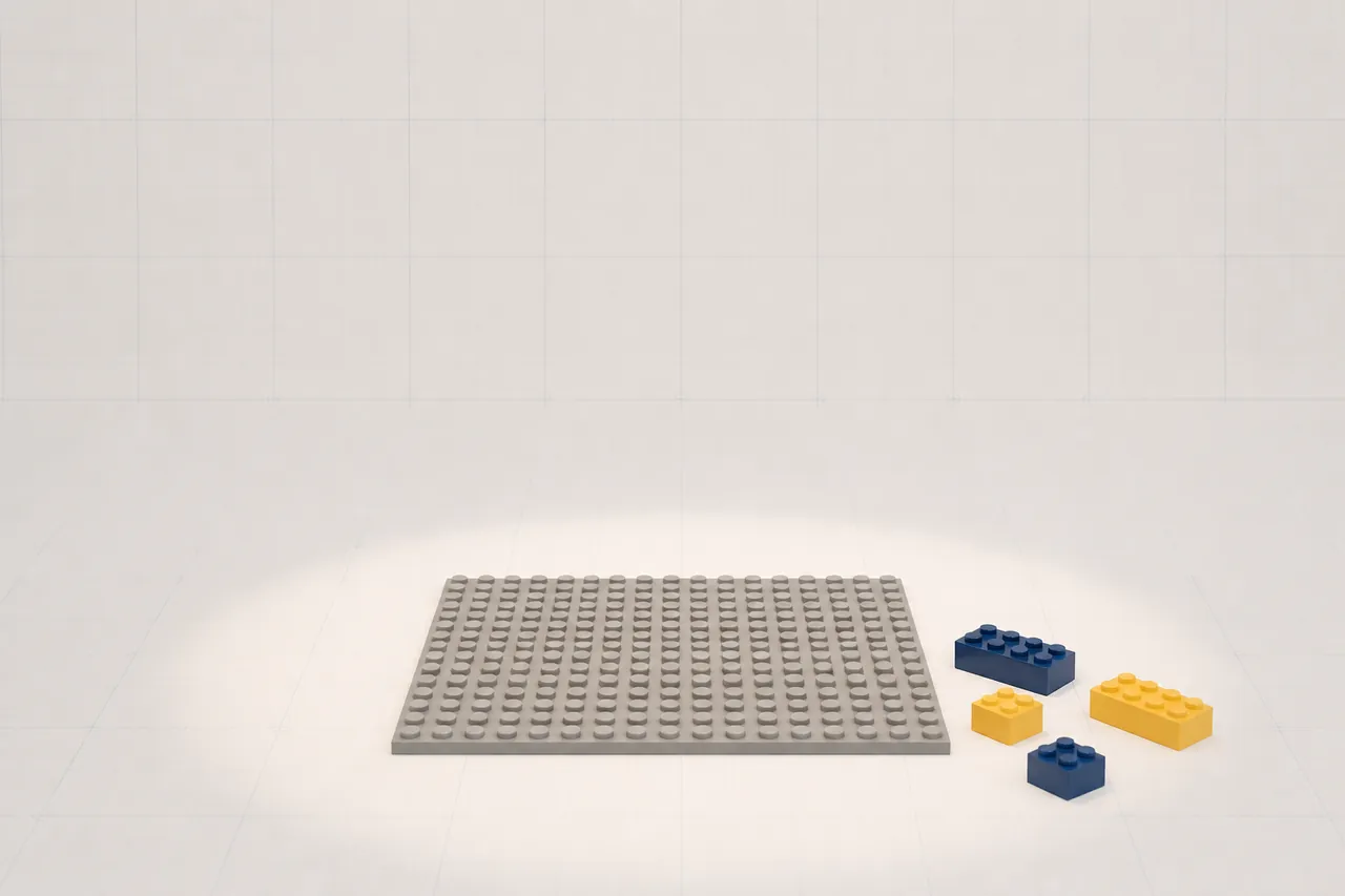 An empty grey brick baseplate under a soft spotlight with a few loose navy and yellow bricks beside it.